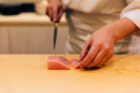 Japanese Omakase Chef cut Medium Fatty Bluefin Tuna (Chutoro in Japanese) neatly by knife on wooden kitchen counter for making sushi. Japanese luxury meal.の写真素材