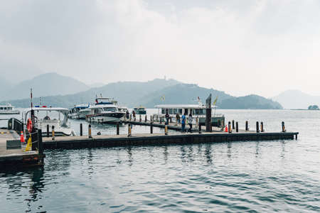 Wooden walkway the lead to the boat in Sun Moon Lake with mountain and cloud in background at...