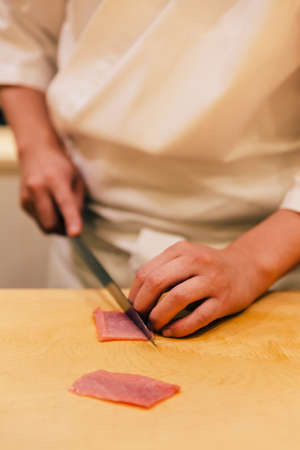 Japanese Omakase Chef cut Medium Fatty Bluefin Tuna, neatly by knife on wooden kitchen counter for making sushi. Japanese luxury meal.の写真素材