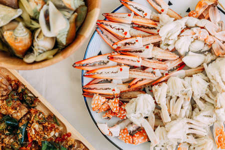 Top view of steamed Flower Crabs and Giant Mud Crabs with separated parts of steamed crab such as claw meat and body with grilled Laevistrombus Canarium in shell.の写真素材