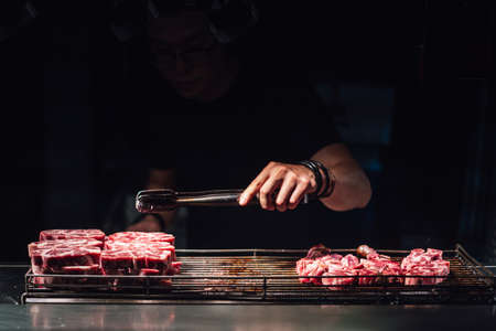 Chef is selecting a raw beef cube by tong for cooking with blow-torched in medium rare, Juicy and tasty. Street food of Jiantan, Taipei, Taiwan.の写真素材