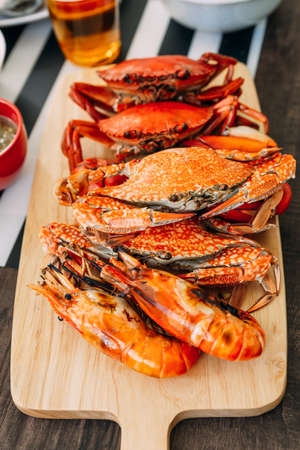 Steamed Giant Mud Crabs, Steamed Flower Crabs and Grilled Shrimps (Prawns) in wooden chopping board.の写真素材
