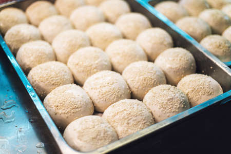 Sheng Jian Bao: White pork bun topping with sesame before fry. Street food of Jiantan in Taipei,...