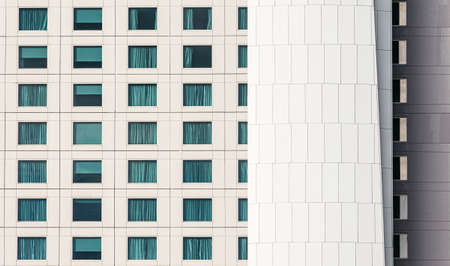 Modern building facade with window glasses sky color reflected and some lighted from the inside with...