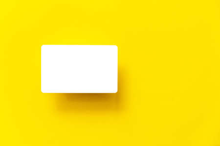 Top view of empty white business card with shadow on the yellow paper background.