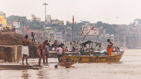 Floating boats and diversity of Indian people living at the ghat with old buildings on background along the Ganges (Ganga) river in Varanasi, Uttar Pradesh, India.のeditorial素材