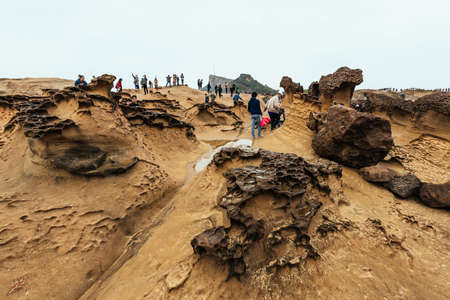 Diversity of tourists walking in Yehliu Geopark, a cape on the north coast of Taiwan. A landscape of honeycomb and mushroom rocks eroded by the sea.のeditorial素材