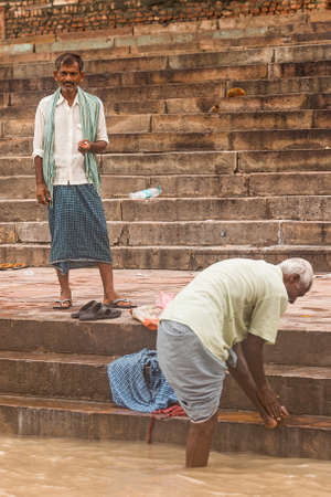 Street photography of Indian people living at the ghat with old buildings on background along the Ganges (Ganga) river in Varanasi, Uttar Pradesh, India.のeditorial素材