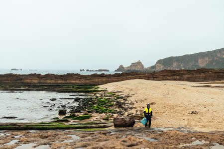 Coast guard is cleaning beach by collecting garbage for dropping in trash in Yehliu Geopark, a cape on the north coast of Taiwan.のeditorial素材