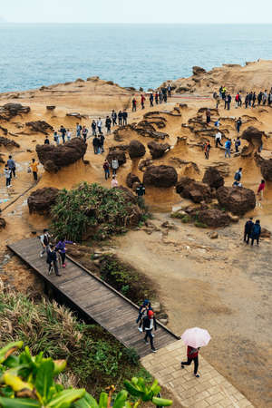 Diversity of tourists walking in Yehliu Geopark, a cape on the north coast of Taiwan. A landscape of honeycomb and mushroom rocks eroded by the sea.のeditorial素材