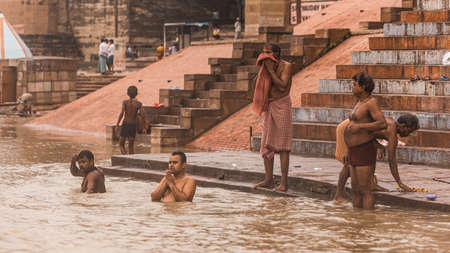 Indian people live, pray and take a bath in the Ganges (Ganga) river at the ghat with old buildings in background in Varanasi, Uttar Pradesh, India.のeditorial素材
