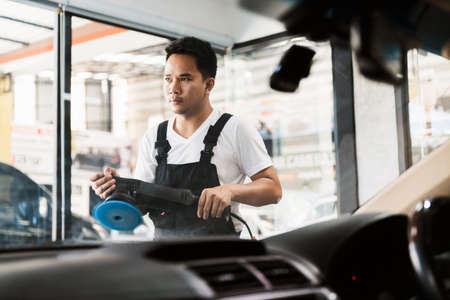 Professional car polishing rubs orbital polisher to polishing on the black car hood, remove scratch...