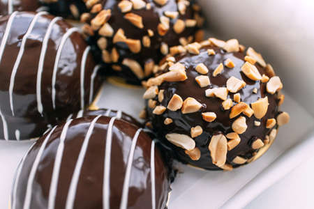 Chocolate covered Bavarian cream donut topping with crush peanuts in paper box. Tasty dessert pasrty.の写真素材