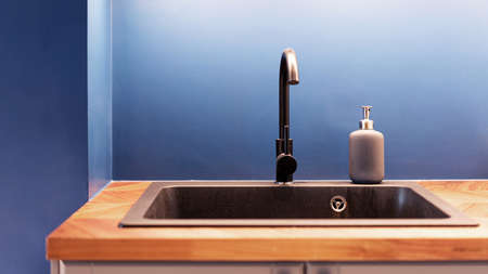 Kitchen sink and faucet. Painted chrome kitchen sink fit in wooden countertop with tap water and liquid soap pump bottle. The contemporary interior of the modern kitchen for home and apartmentの写真素材