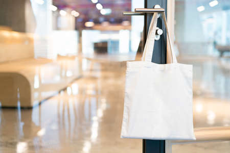 Tote bag canvas fabric for mockup blank template, hanging on a doorknob in the meeting room in the office with blur background.の写真素材