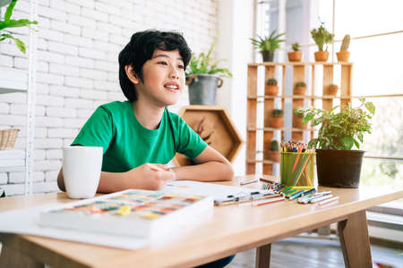The child's drawing with colored pencils on white paper with smiling on a wooden table. Children's creativity expressed through art in kindergarten and elementary school. back to school.の写真素材