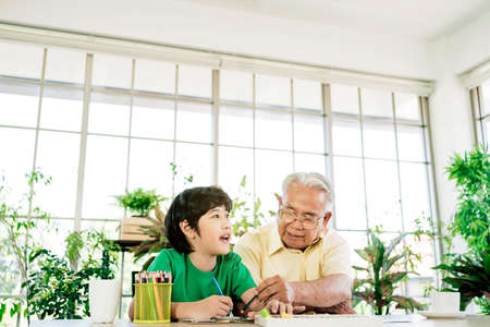 Asian retirement grandfather and his grandson spending quality time together insulated at home.