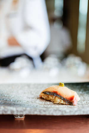 Shima Aji Sushi with fresh wasabi served by hand on a stone black plate.の写真素材