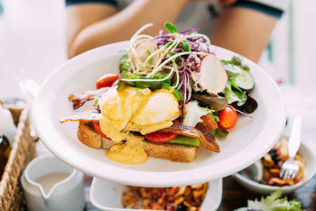 Eggs Benedict served with toast, crispy bacon, asparagus, sliced tomato and rocket salad mix with...