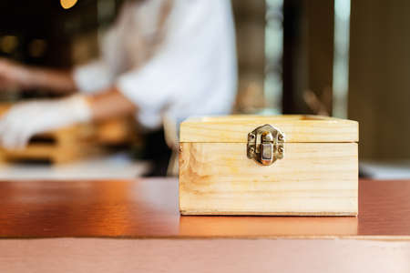 Japanese Omakase meal: front view of a wooden box with secret food inside with blur Omakase chef in the background. Image with copy space.の写真素材