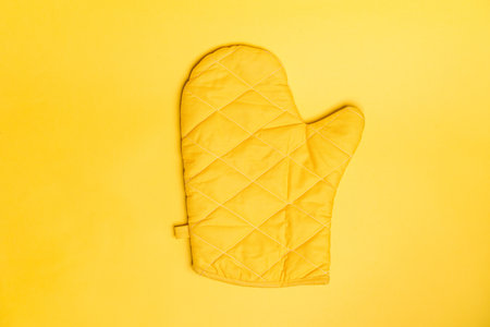 Top view of yellow oven gloves on yellow color background. Mockup for food banner and kitchen protection equipment.の写真素材