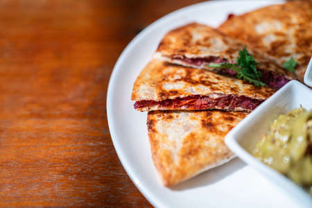 Close-up of Vegan Quesadilla: grilled whole-wheat tortilla filled with sweet potato and red bean,...