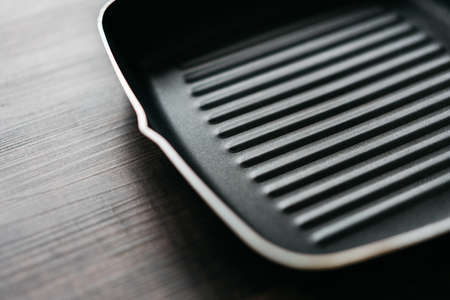Close-up the empty non-stick square frying pan over wooden kitchen counter background with copy space.の写真素材