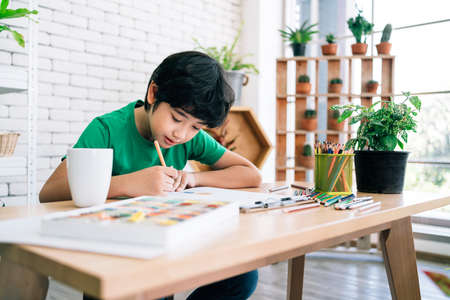 The child's drawing with colored pencils on white paper with smiling on a wooden table. Children's creativity expressed through art in kindergarten and elementary school. back to school.の写真素材