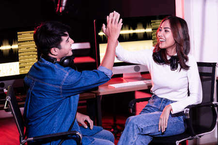 A pretty Asian female give hi-five with her producer in the studio in a rehearsal session....