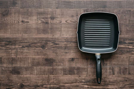 Top view of the empty non-stick square frying pan over wooden kitchen counter background with copy space.の写真素材
