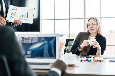 Caucasian businesswoman sitting and holding a cup of coffee while listening to a partnership...