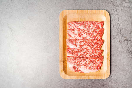 Premium Rare Slices sirloin Wagyu A5 beef with high-marbling texture on a wooden plate. Served for Yakiniku, Sukiyaki and Shabu. Image with copy space.の写真素材