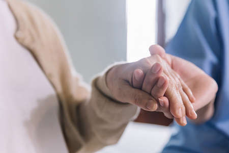 Close-up senior Asian woman hand with her caregiver helping hands holding together, Caregiver visit...