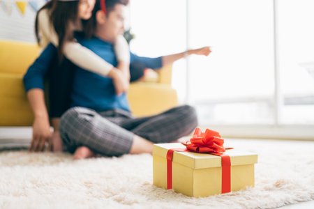 Beautiful gift box and blurred couple spending quality time together during Christmas holiday in the living room couple on background, New year or birthday concept. Image with copy space.の写真素材
