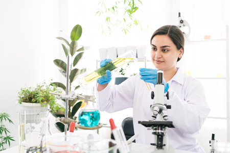 Middle East woman scientist researcher rinse liquid from a graduated cylinder to test tube for analysis of liquids in the lab. Scientist working with test tube and graduated cylinder.の写真素材