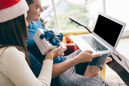 Young happy Asian couple sitting together video call on a laptop with friends or parents thanks for...