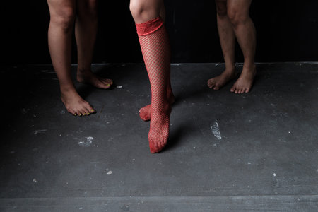 Three women's legs with one of them wearing red stockings in the dark. Ideas to stop violence...