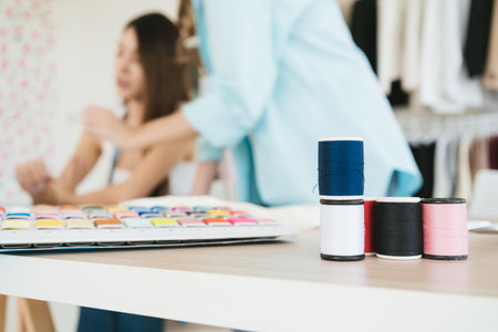 Close-up a group of colorful sewing threads on the table with blur fashion designers or tailors...
