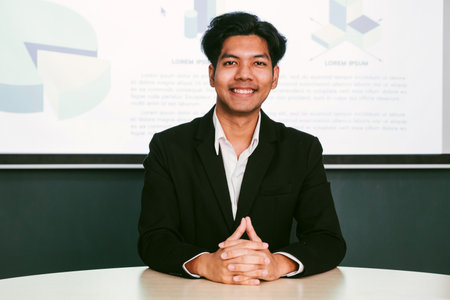 Portrait of successful Asian businessman inside the office is looking at the camera, talking on a...
