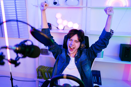Portrait of Asian male gamer celebrating victory in front of the gaming table. Gamer winning an esports game with victory emotion. The player rejoices in victory in the competition.の写真素材