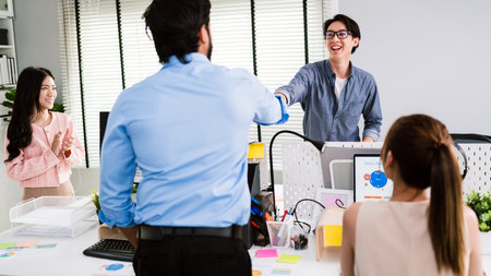 Cheerful Asian businessman partners making fist bump with a smile as a symbol of teamwork. Positive multi-ethnic business colleagues on diversity in the office. Collaboration conceptの写真素材