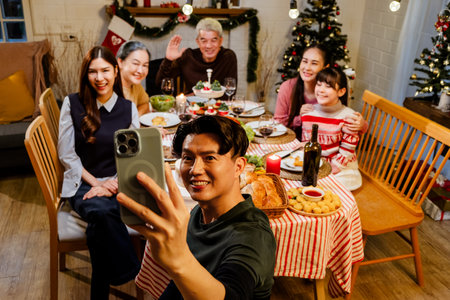 Portrait of father taking selfie with smartphone of family sitting at dinner table celebrating...