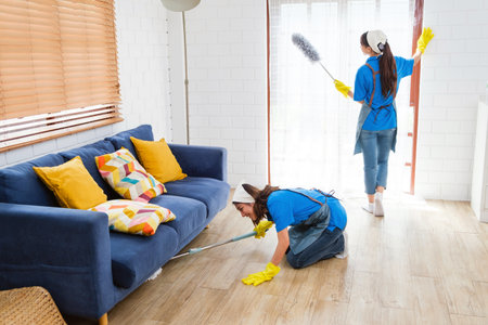 Young professional cleaning service women workers working in the house. Girls housekeeper wiped a...