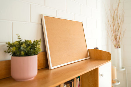 A minimalistic shelf with a cork board, potted plant, and decorative items, creating a cozy, stylish...