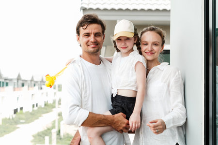 Happy mixed-race family of three enjoying quality time on a balcony in summer attire. Smiling...