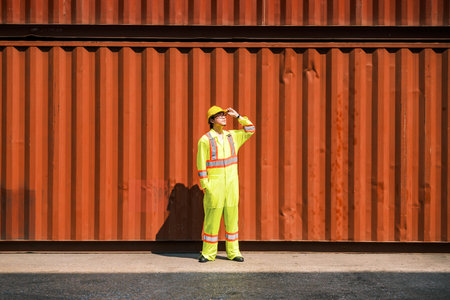 Logistics worker in reflective safety gear standing by a large cargo container, symbolizing global...