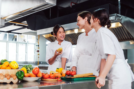 Aspiring chefs in training at a professional cooking class in a chef institute kitchen, learning culinary skills with fresh ingredients, teamwork, and hands-on food preparation under supervision.の写真素材