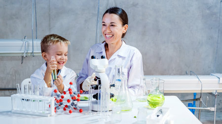 A happy child and female scientist conduct a chemistry experiment in a bright lab. They explore eco-friendly farming innovations and science learning through hands-on experiments and teamwork.の写真素材