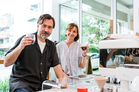 Smiling couple enjoying fresh coffee at a cozy cafe counter. Relaxed atmosphere highlights lifestyle moments, coffee culture, and friendly service in a bright, modern urban coffee shop.の写真素材