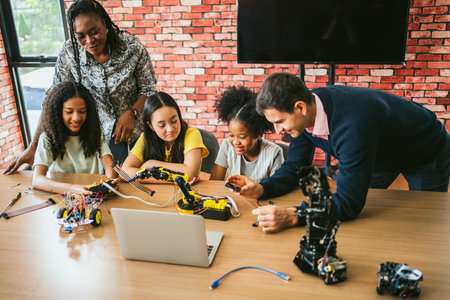 Students and mentors collaborate on robotics projects in classroom, assembling kits and coding at a...